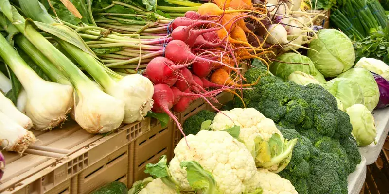 Frisches Gemüse am Marktstand: Frühlingszwiebeln, Radieschen, Karfiol und Brokkoli in Kisten